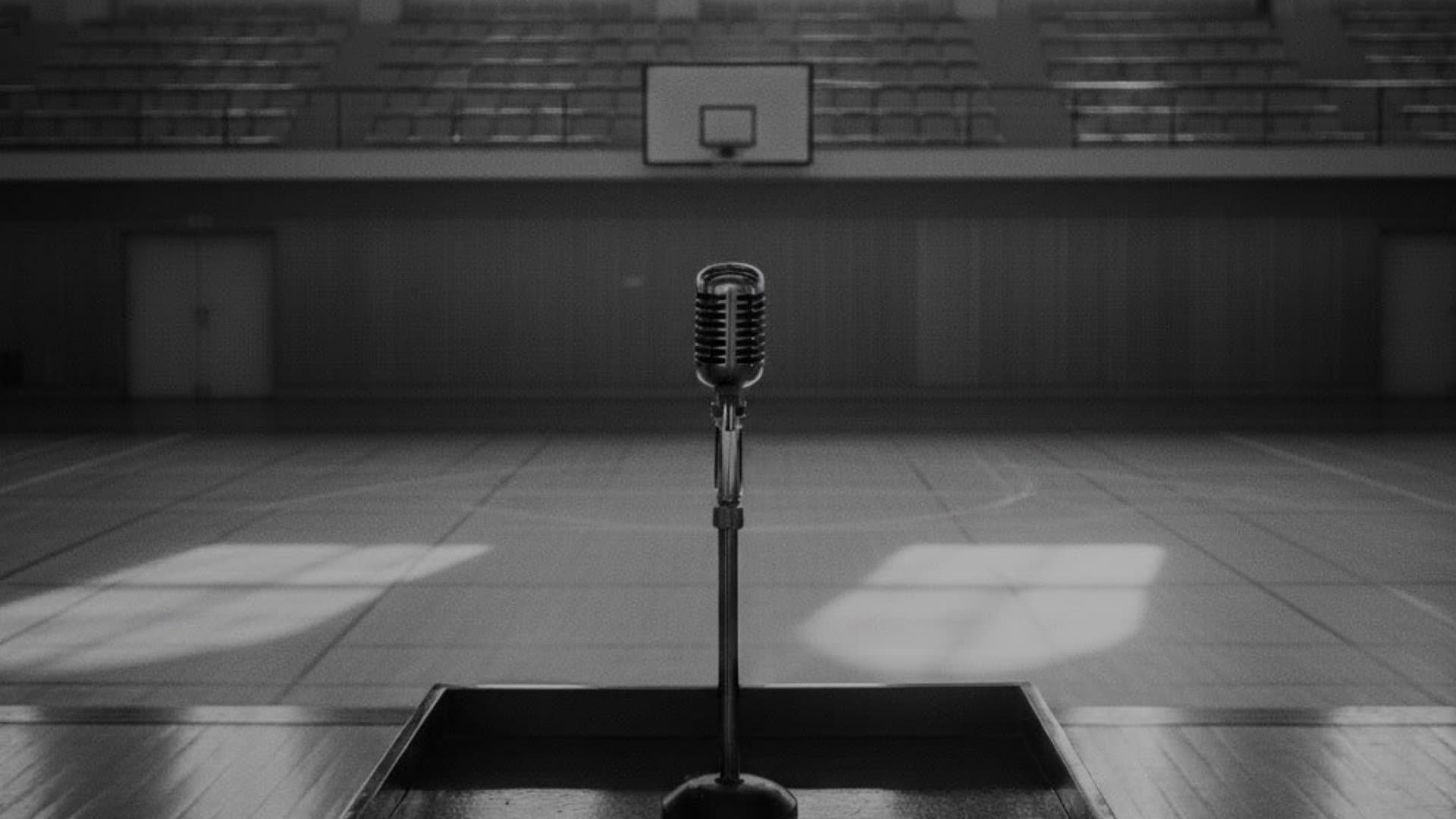 無人の小学校の体育館。壇上にマイクがセットされている