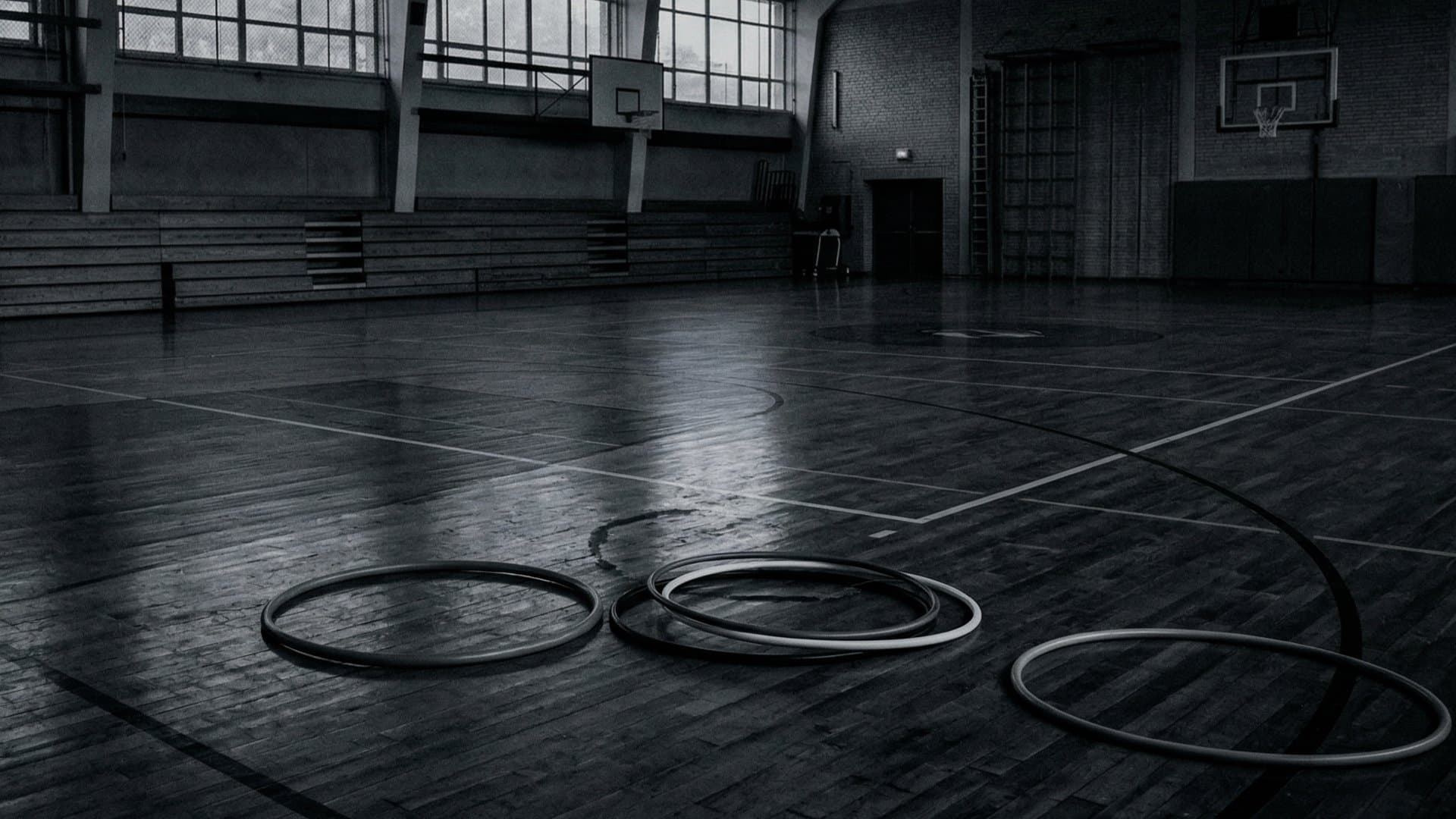 無人の体育館に象徴的にフラフープが5個ほど並べられている