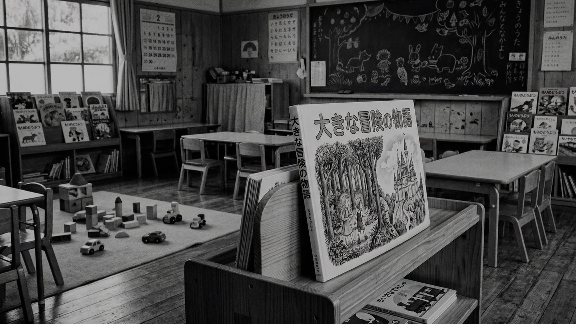 誰もいない保育園の部屋。おもちゃが床に並んでいる。本棚に立てかけられた絵本。